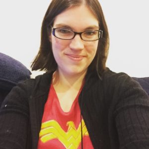 Photo of a white woman in a red and gold Wonder Woman shirt and black sweatshirt looking at the camera in a selfie.