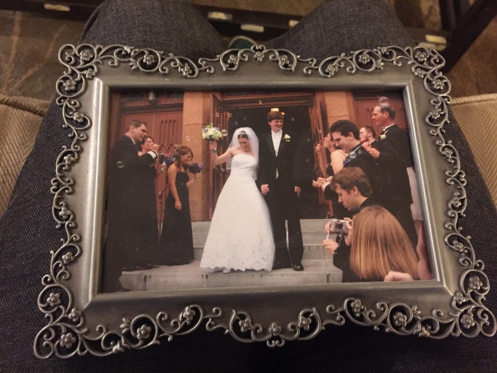 Photo: Framed photograph of a white man and woman walking down stairs in wedding clothes, surrounded by people on both sides