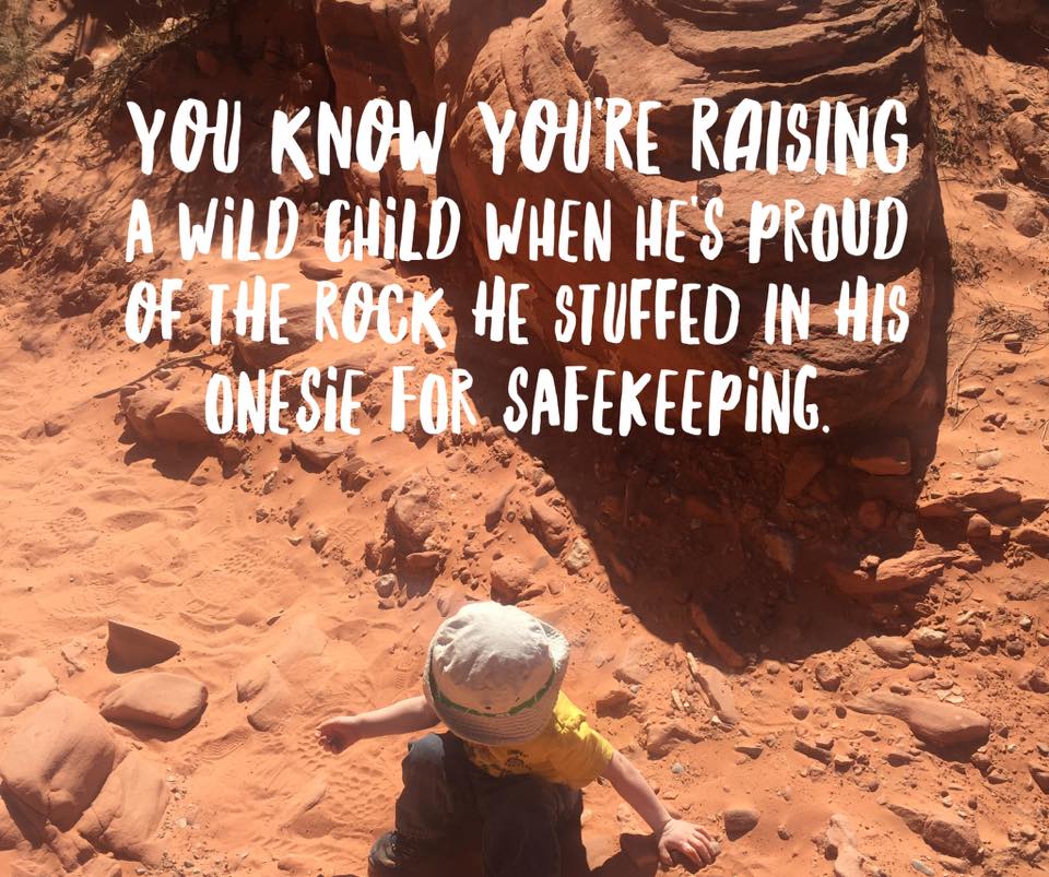 You know you're raising a wild child when he's proud of the rock he stuffed in his onsie for safekeeping. (Photo: Small child with a floppy hat sitting in red sand)