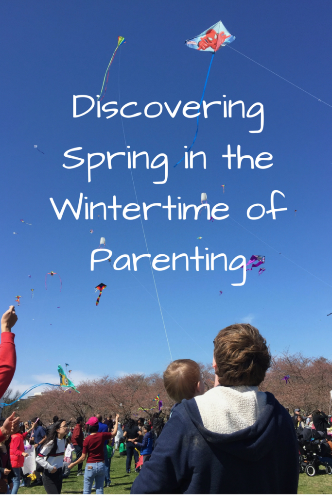 Discovering Spring in the Wintertime of Parenting. (Photo: Adult holding a child with kites in the background against the sky)