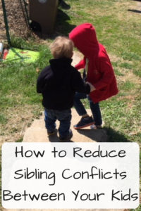 How to Reduce Sibling Conflicts Between Your Kids (Photo: Two young white children walking down concrete stairs with the older one helping the younger)