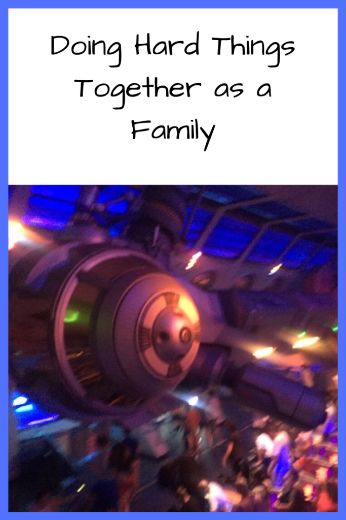 Photo: Large space-ship looking object hanging from the ceiling in a darkened room; Text: Doing Hard Things Together as a Family