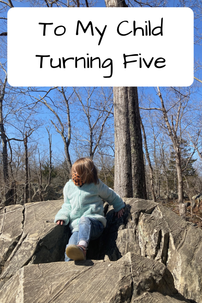 To My Child Turning Five (Photo of a kid in a fuzzy jacket with a mask sitting on a rock)
