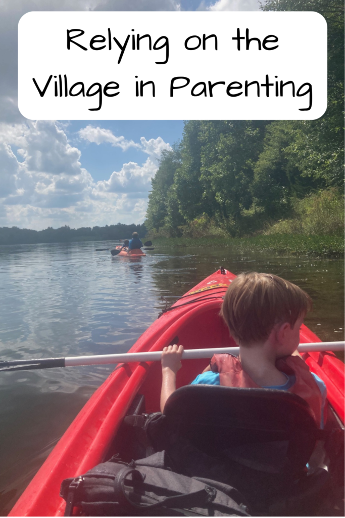 Relying on the Village in Parenting; photo of a white boy in a red kayak on a lake