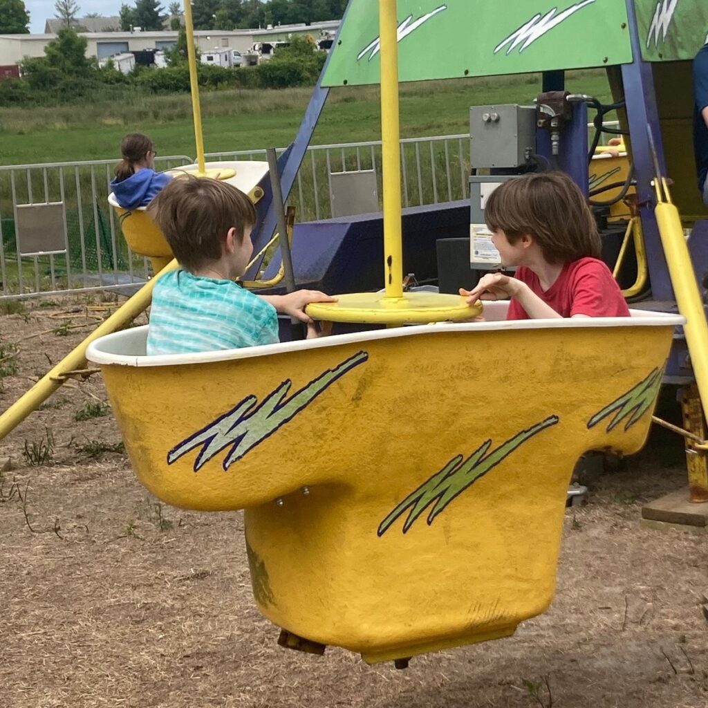 Photo of my kids (two white boys in t-shirts) in a carnival ride that has a bucket on an arm that spins around