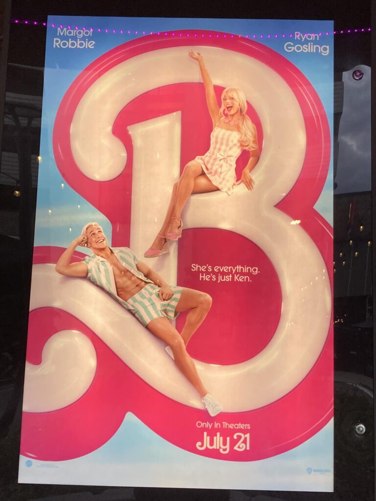 The Barbie movie poster, which has a giant B with Barbie and Ken sitting on it and the text “She’s everything. He’s just Ken.” 