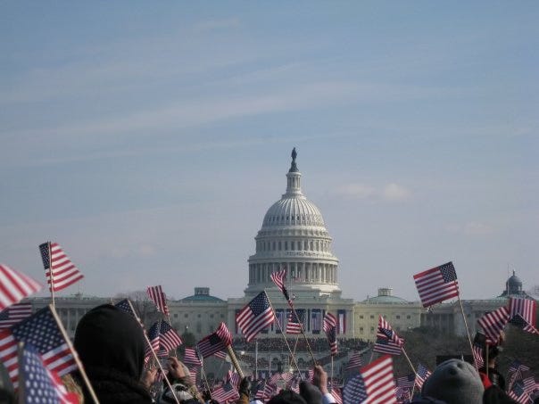 The U.S. capital building with a huge crowd of people waving American flags in front of it