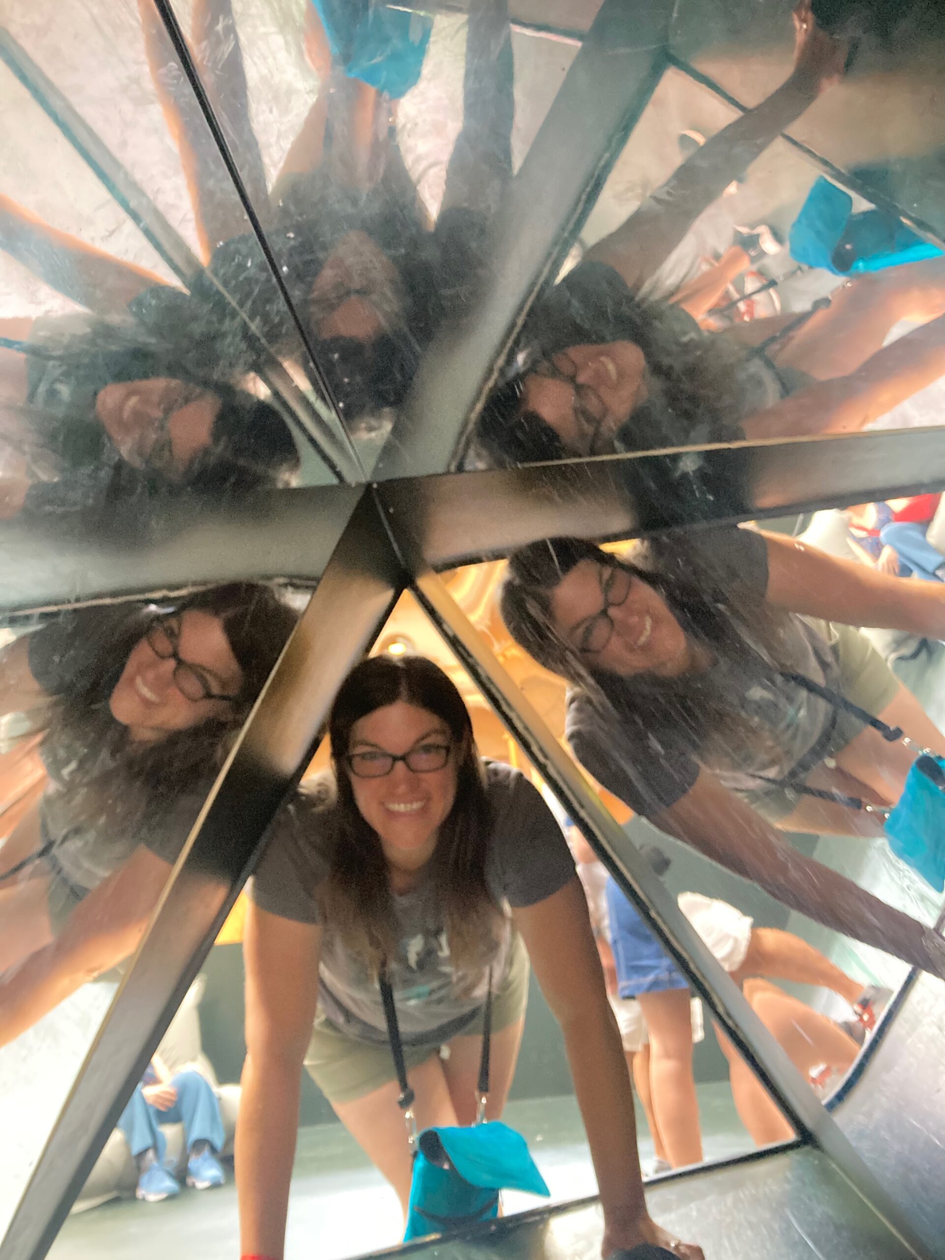 Me (Shannon), a white, brown haired woman looking through a giant kaleidoscope with my image reflected six times