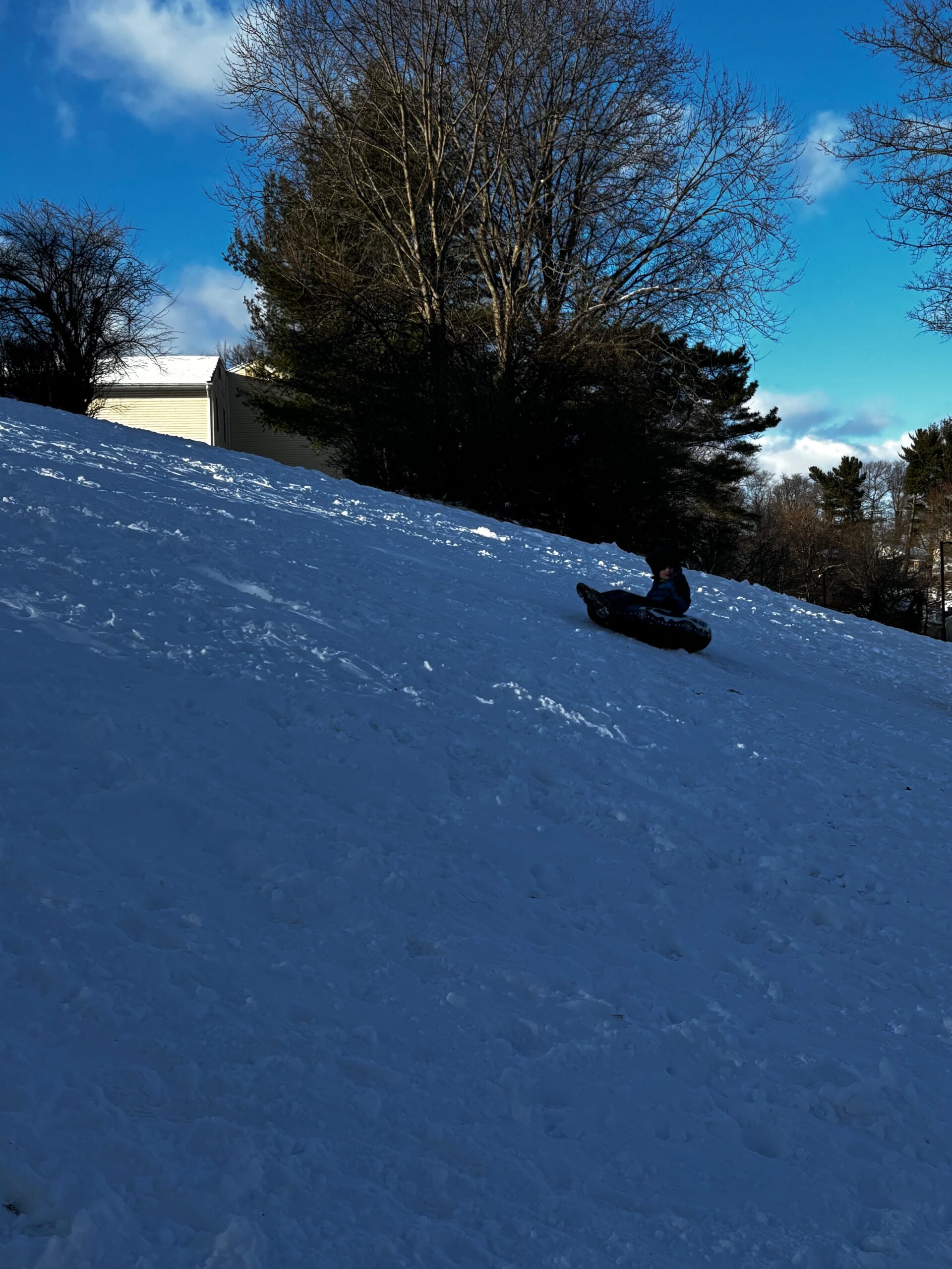 A kid sliding down a snow-covered steep hill in the twilight